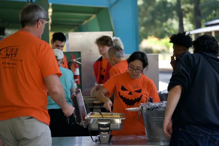 Woman scooping hot food at outdoor banquet