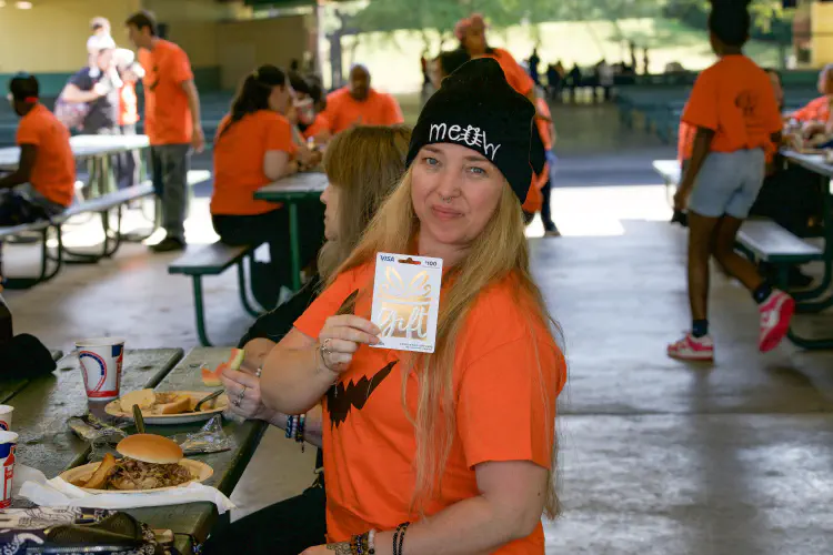 Woman smiling holding gift card at outdoor banquet