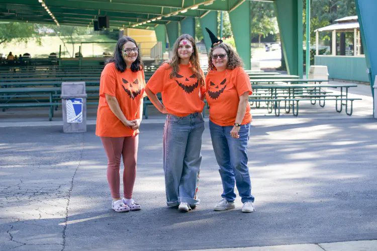 Teens and mother standing, smiling at halloweeen event